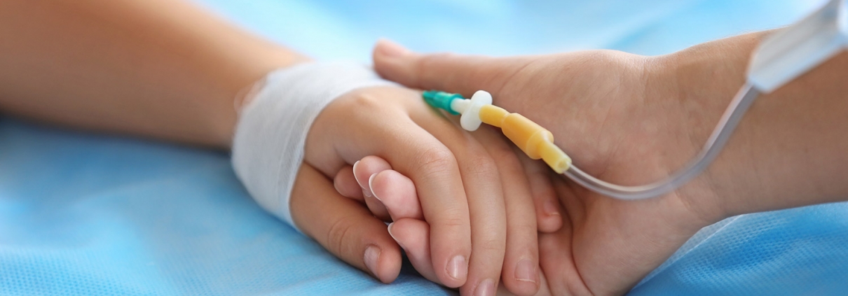 Child hand with catheter on bed