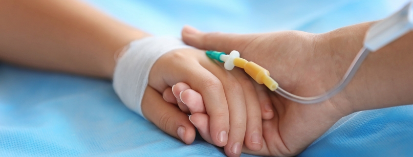 Child hand with catheter on bed