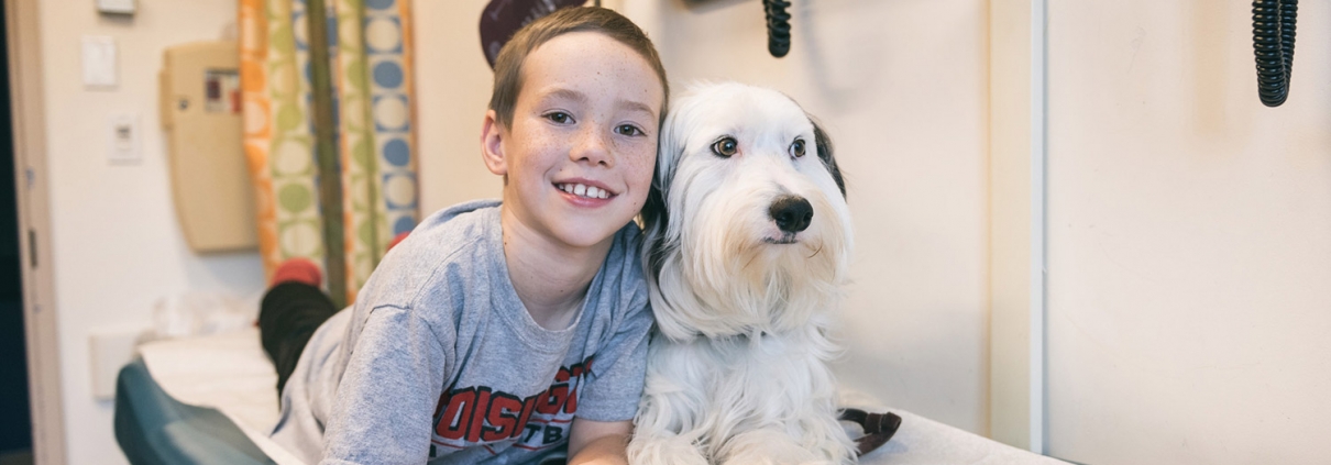 boy with dog on examination bed in hospital smiling for camera