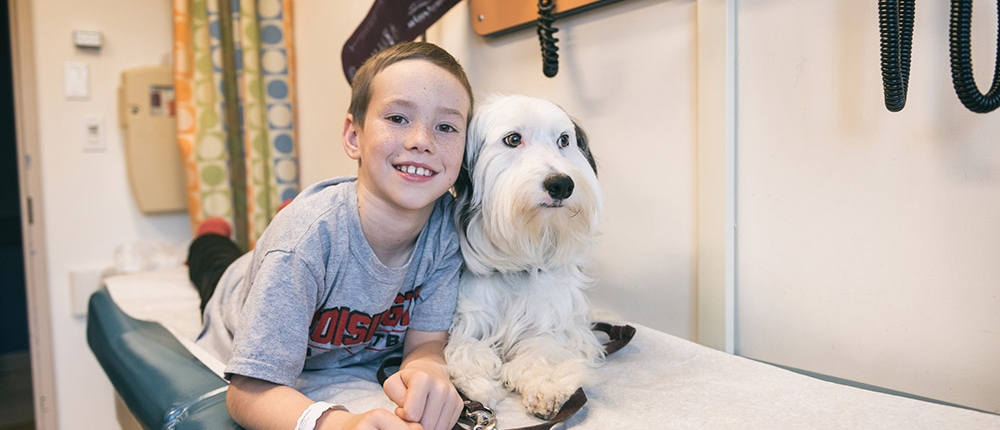 boy with dog on examination bed in hospital smiling for camera